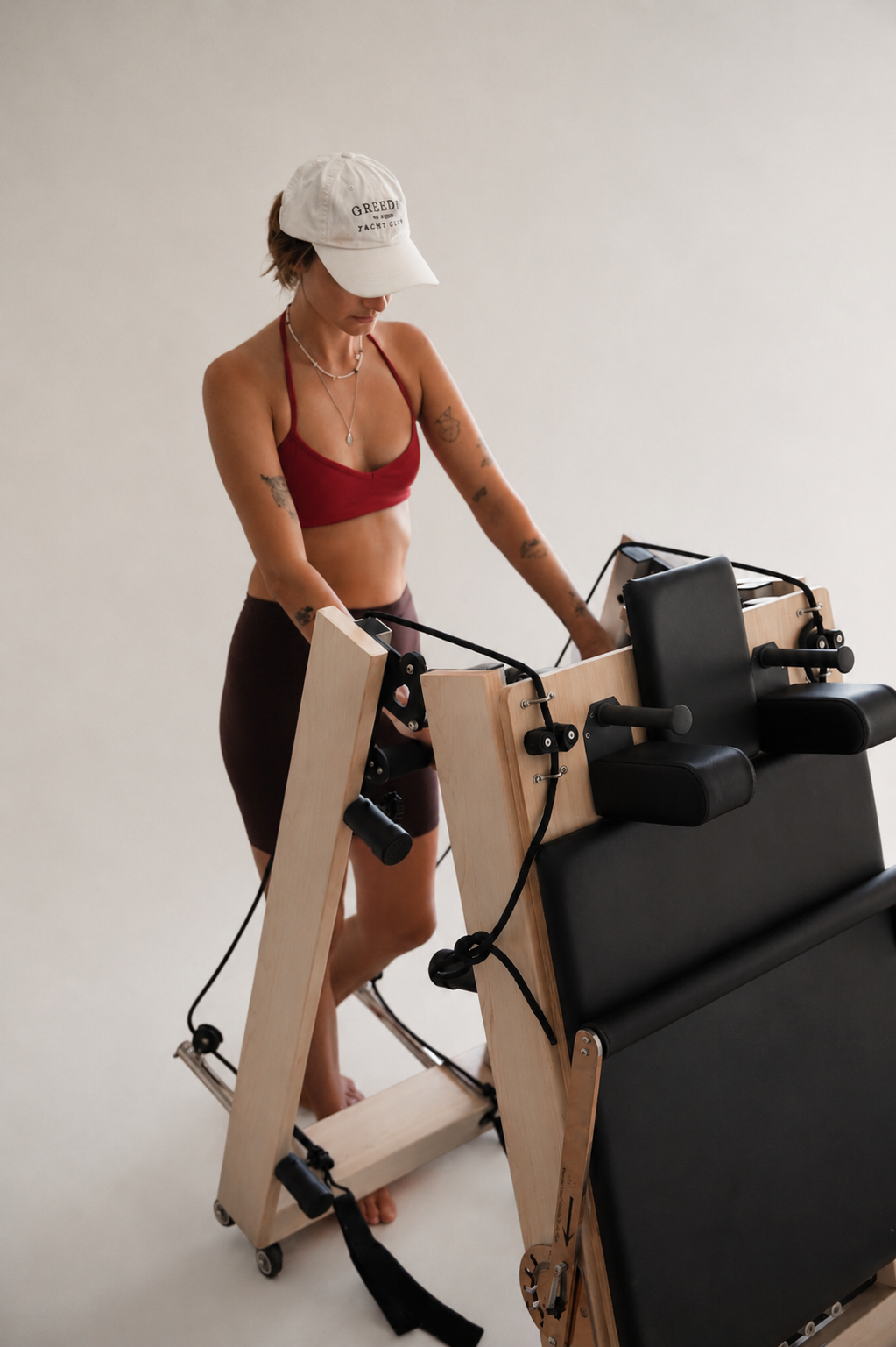 Woman folding a wooden Pilates reformer after a home workout