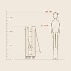 Reformer Pilates pieghevole alto 117 cm da chiuso, mostrato in scala accanto a una persona alta 167 cm