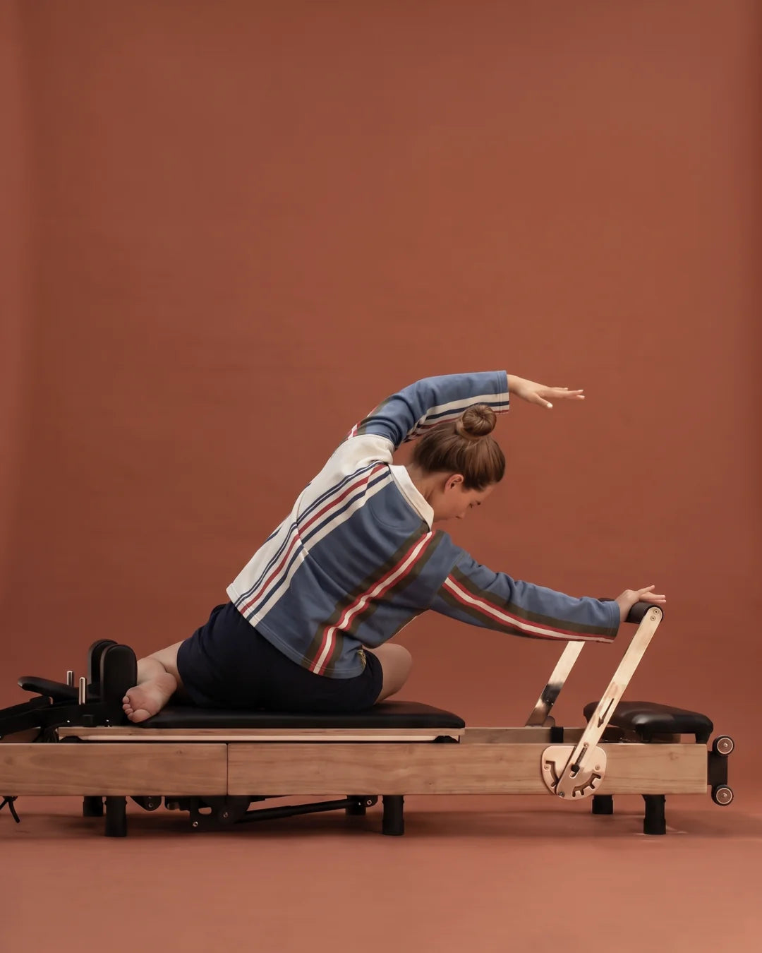 Woman doing a mermaid stretch on a folding Pilates reformer