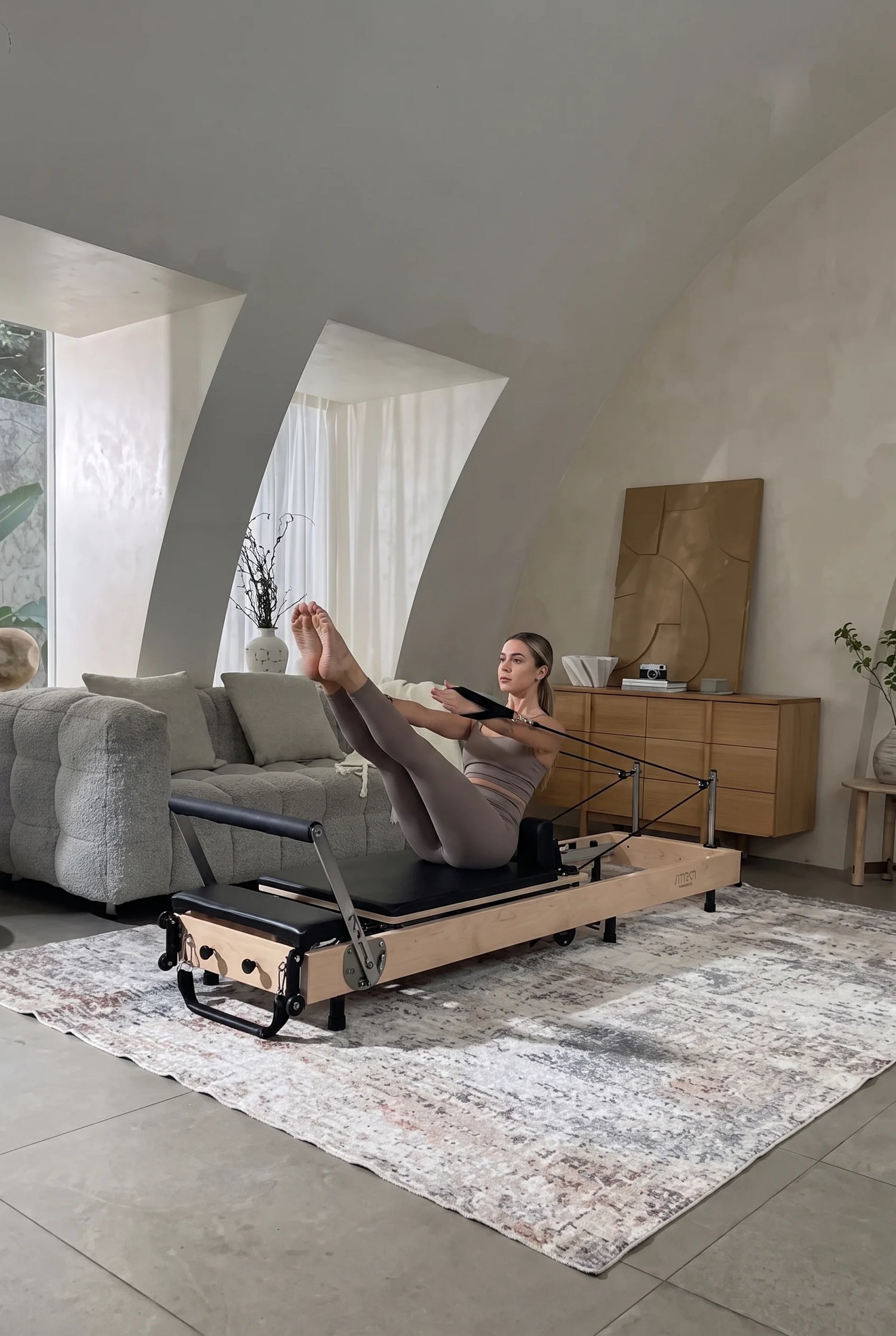 Woman performing a stretch on a wooden foldaingPilates reformer