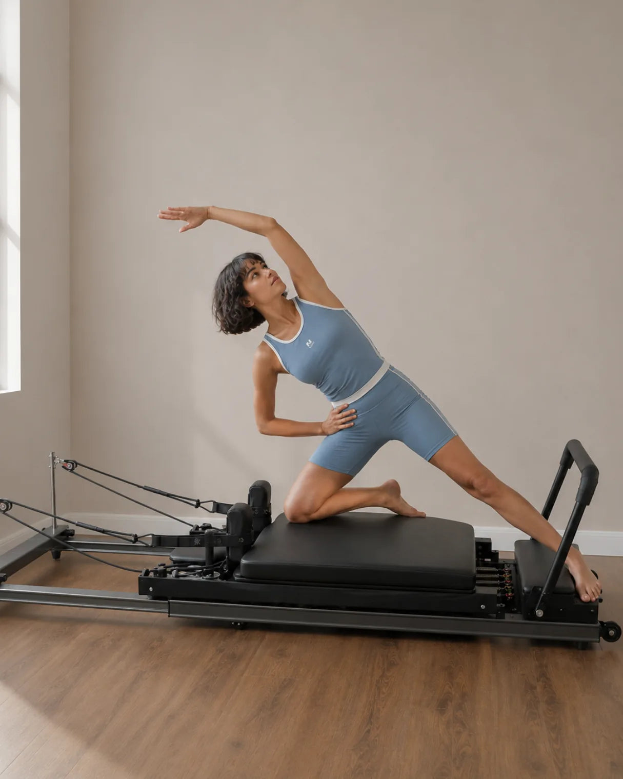Mujer realizando un estiramiento lateral en un reformer de Pilates telescópico