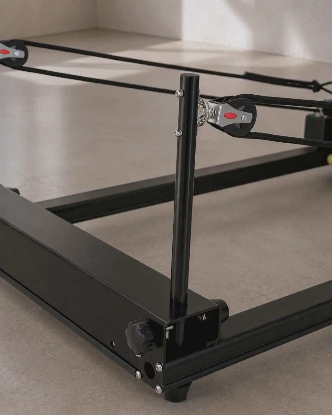 Primer plano de la barra de pies ajustable y la polea de un Reformer de Pilates